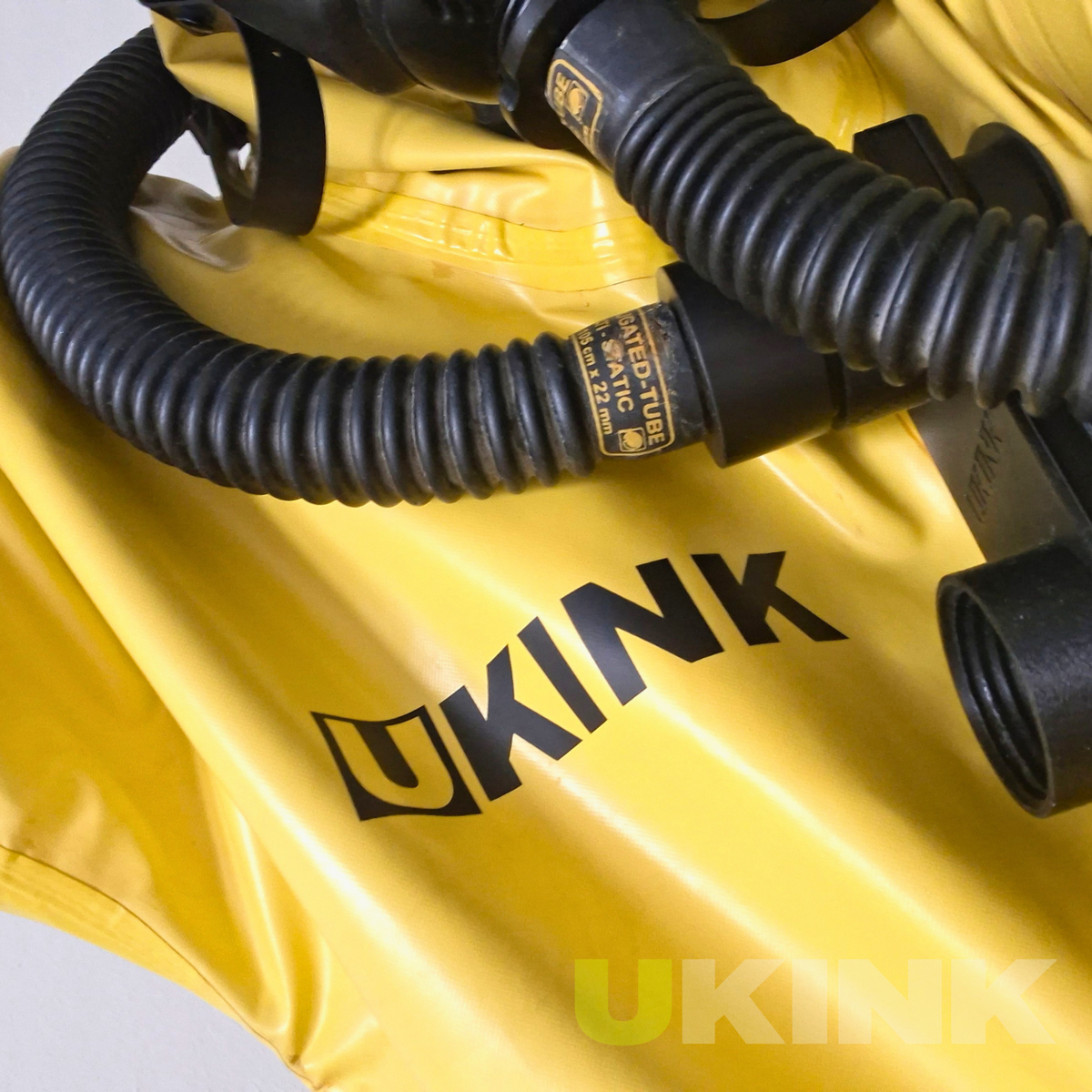 Individuelle schwarze Vinylbeschriftung mit UKINK Schriftzug auf einem gelben Gummianzug mit schwarzem Atemschlauch
