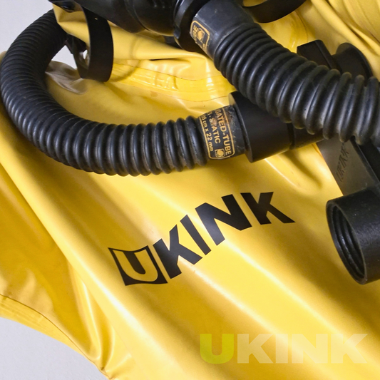 Individuelle schwarze Vinylbeschriftung mit UKINK Schriftzug auf einem gelben Gummianzug mit schwarzem Atemschlauch