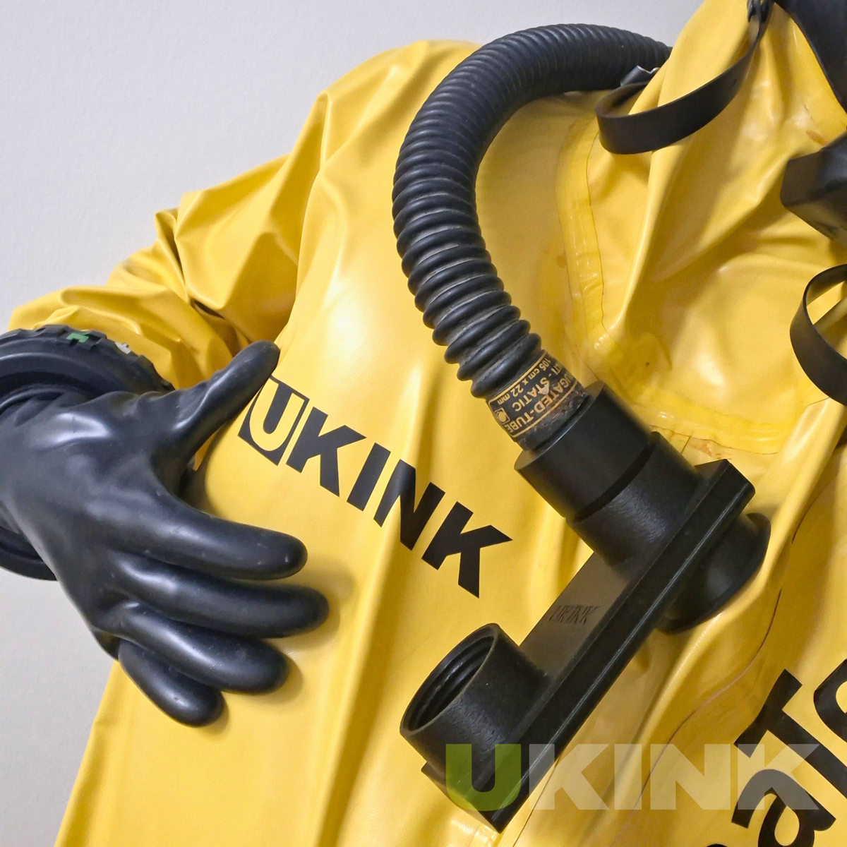 Personalisierte UKINK Beschriftung in Schwarz matt auf gelbem Industrial Gummianzug mit schwarzem Handschuh und Atemschlauch